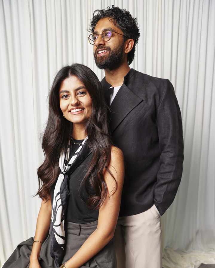 May and Rish, founders of Rumy Portraits, smiling in front of an ivory drape